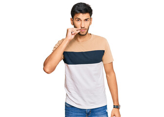 Young handsome man wearing casual clothes mouth and lips shut as zip with fingers. secret and...
