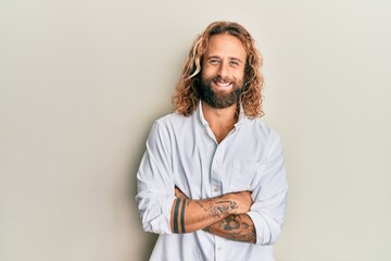 Handsome man with beard and long hair wearing casual white shirt happy face smiling with crossed...