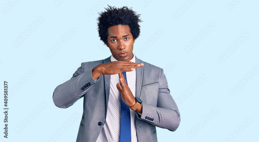 Poster Handsome african american man with afro hair wearing business jacket doing time out gesture with hands, frustrated and serious face