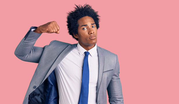 Handsome african american man with afro hair wearing business jacket strong person showing arm muscle, confident and proud of power