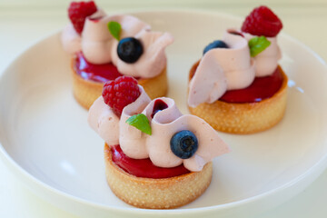 Close up of berry tartlets with fresh berries and whipped ganashe