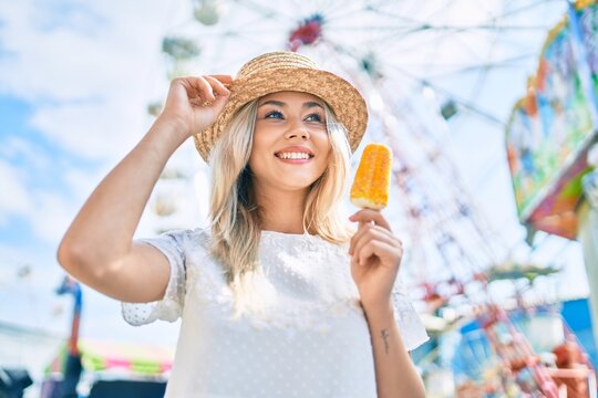 Young caucasian tourist girl smiling happy and eating ice cream at fairground.