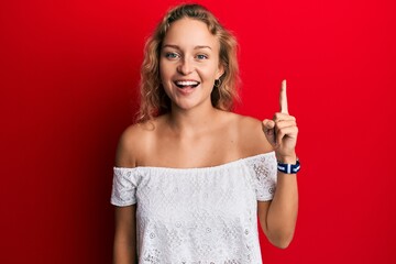 Beautiful caucasian woman wearing casual clothes over red background pointing finger up with successful idea. exited and happy. number one.