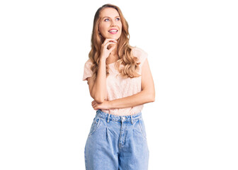 Young beautiful caucasian woman with blond hair wearing casual clothes with hand on chin thinking about question, pensive expression. smiling and thoughtful face. doubt concept.