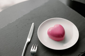Delightful, luxury, romantic mousse cake in the form heart served on a white plate.. Valentine's Day on February 14. Dark Background.