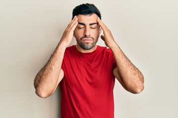 Young hispanic man wearing casual clothes with hand on head, headache because stress. suffering migraine.