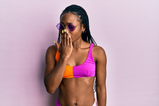 Young african american woman wearing bikini and sunglasses bored yawning tired covering mouth with hand. restless and sleepiness.