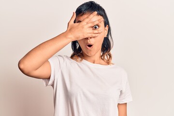 Fototapeta premium Young woman wearing casual clothes peeking in shock covering face and eyes with hand, looking through fingers afraid