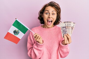 Young brunette woman holding mexico flag and mexican pesos banknotes celebrating crazy and amazed...