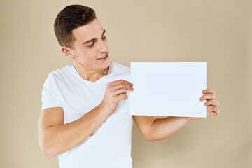 man in white t-shirt sheet of paper in hands Copy Space cropped view beige background