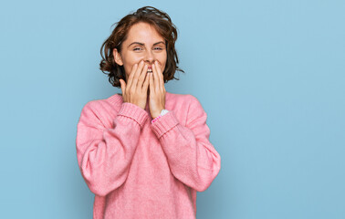 Young hispanic woman wearing casual clothes laughing and embarrassed giggle covering mouth with...