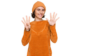Young hispanic woman wearing casual clothes and wool cap showing and pointing up with fingers...