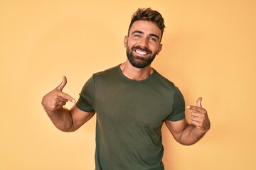 Young hispanic man wearing casual clothes looking confident with smile on face, pointing oneself...