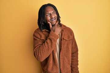 African american man with braids wearing brown retro jacket thinking worried about a question, concerned and nervous with hand on chin