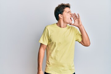 Handsome caucasian man wearing casual clothes shouting and screaming loud to side with hand on mouth. communication concept.