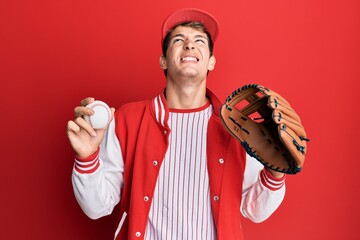 Handsome caucasian man wearing baseball uniform holding golve and ball angry and mad screaming...