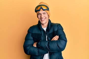 Handsome caucasian man wearing snow wear and sky glasses happy face smiling with crossed arms looking at the camera. positive person.