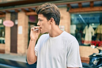 Fototapeta na wymiar Young caucasian man with serious expression smoking cigarette at the city.