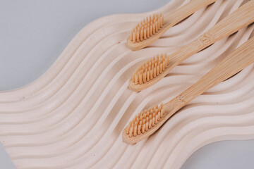 Trendy still life composition with natural bamboo toothbrushes on wavy plaster mold background with copy space. Sustainable lifestyle, zero waste home. Selective focus, mockup