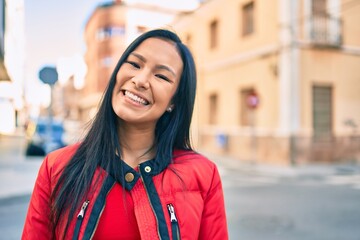 Young latin woman smiling happy walking at the city.