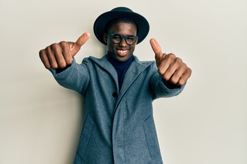 Young african american man wearing elegant style approving doing positive gesture with hand, thumbs up smiling and happy for success. winner gesture.