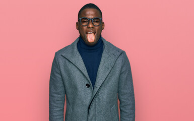 Young african american man wearing business clothes and glasses sticking tongue out happy with funny expression. emotion concept.