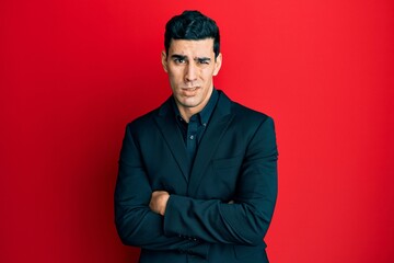 Obraz premium Handsome hispanic business man with arms crossed gesture clueless and confused expression. doubt concept.