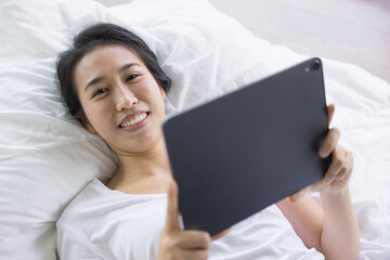 woman using digital tablet in a bed at home. The use of concept of new generation, family, parenthood, authenticity, connection, technology.