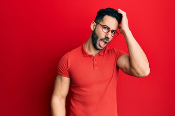 Young hispanic man wearing casual clothes and glasses surprised with hand on head for mistake, remember error. forgot, bad memory concept.