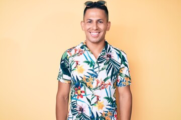 Young handsome latin man wearing summer clothes with a happy and cool smile on face. lucky person.