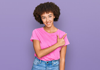 Young hispanic girl wearing casual clothes cheerful with a smile of face pointing with hand and finger up to the side with happy and natural expression on face