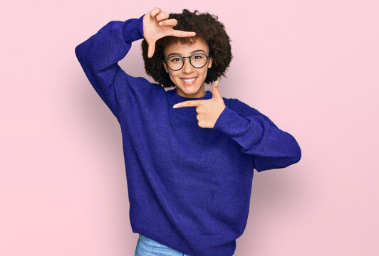 Young hispanic girl wearing casual winter sweater and glasses smiling making frame with hands and fingers with happy face. creativity and photography concept.