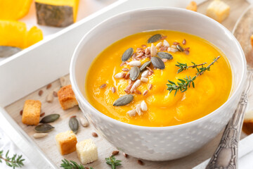 Creamy pumpkin soup with carrots garnished with mixed seeds and thyme