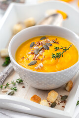 Creamy pumpkin soup with carrots garnished with mixed seeds and thyme