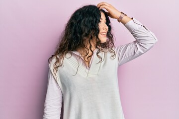 Young brunette woman with curly hair wearing casual clothes smiling confident touching hair with hand up gesture, posing attractive and fashionable