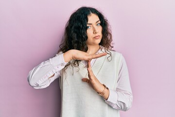 Young brunette woman with curly hair wearing casual clothes doing time out gesture with hands,...