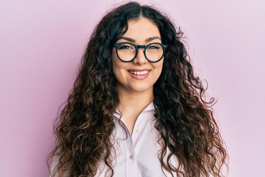 Young brunette woman with curly hair wearing casual clothes and glasses with a happy and cool smile on face. lucky person.