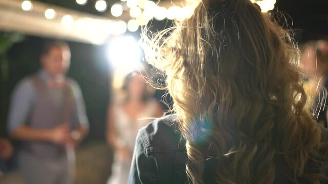 girl dancing in the spotlight, her hair fluttering, view from the back