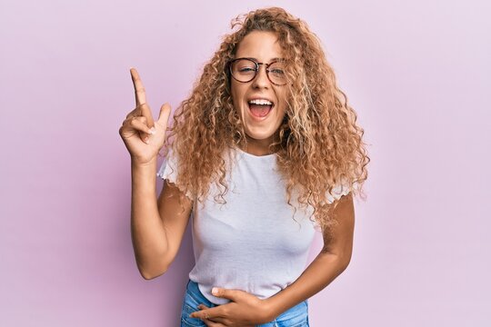 Beautiful caucasian teenager girl wearing white t-shirt over pink background pointing finger up with successful idea. exited and happy. number one.