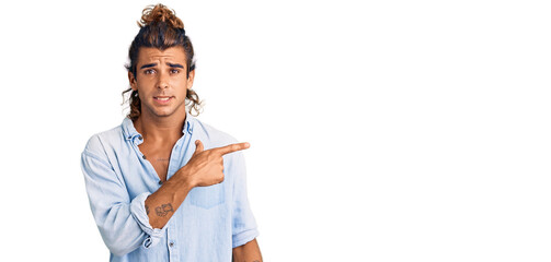 Young hispanic man wearing summer style pointing aside worried and nervous with forefinger,...