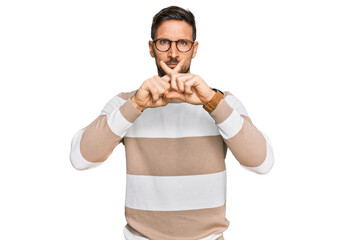 Handsome man with beard wearing casual clothes and glasses rejection expression crossing fingers...