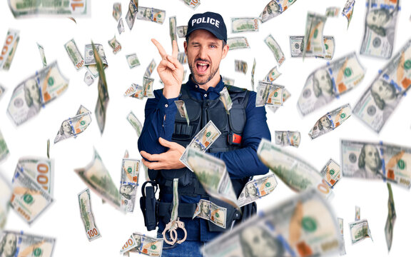 Young handsome man wearing police uniform smiling with happy face winking at the camera doing victory sign with fingers. number two.