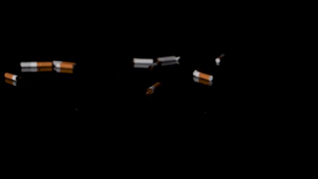 Concept of littering, smashing cigarettes stubs on black reflective floor.