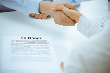 Casual dressed businessman and woman shaking hands after contract signing in white colored office. Handshake concept