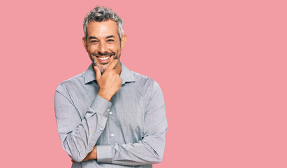 Fototapeta premium Middle age grey-haired man wearing casual clothes looking confident at the camera smiling with crossed arms and hand raised on chin. thinking positive.
