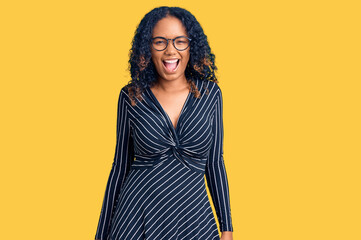 Young african american woman wearing casual clothes and glasses winking looking at the camera with...