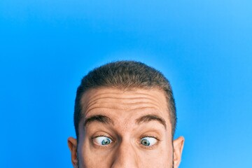 Young caucasian man showing head and half face making fish face with mouth and squinting eyes, crazy and comical.