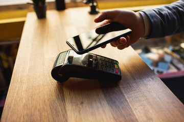 Contactless payment with your smartphone. Paying with a smartphone device on a credit card terminal. Wireless payment.