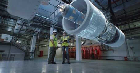 Male engineers discussing engine construction in workshop