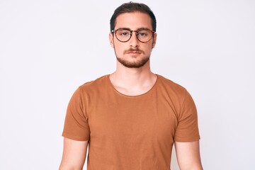 Young handsome man wearing casual clothes and glasses with serious expression on face. simple and natural looking at the camera.